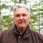 Porträtt av författare Anders Johansson mot en bakgrund av skog.
